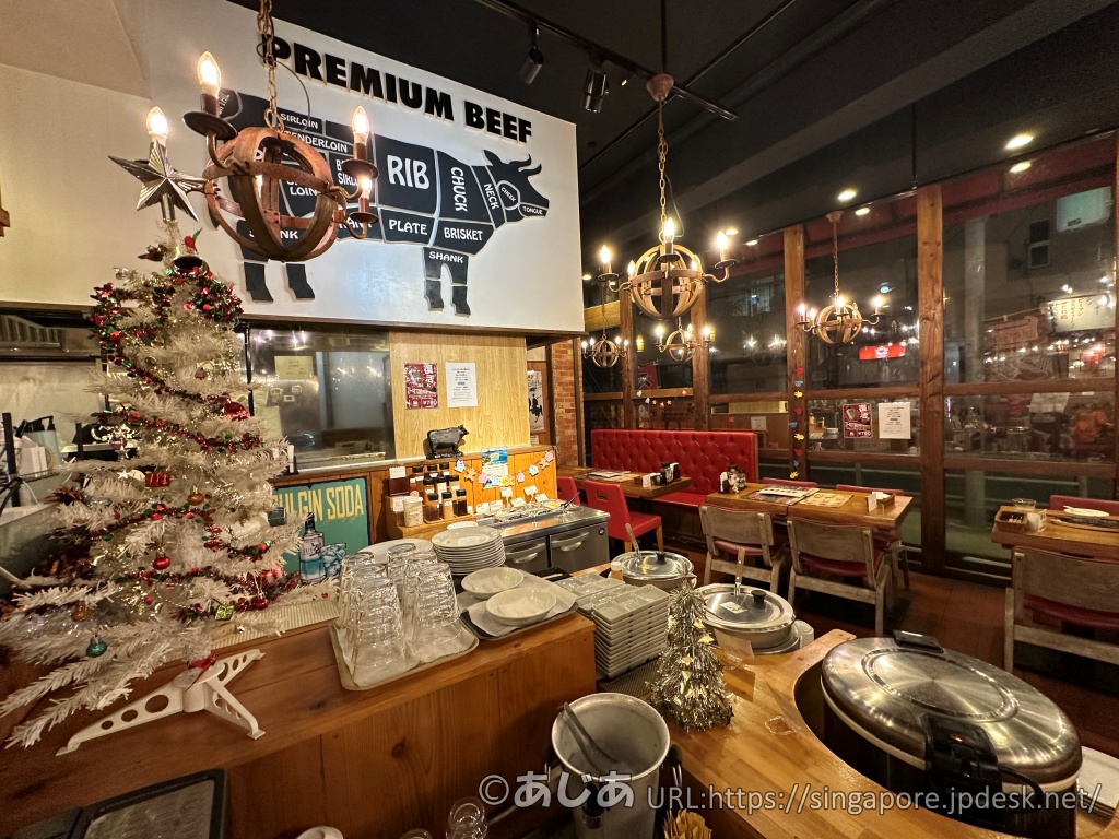 HAN'Sの店内。木目調のカウンターやテーブル席があり、壁には「PREMIUM BEEF」と書かれた牛の部位のイラストがある。シャンデリア風の照明やクリスマスツリーも飾られている。