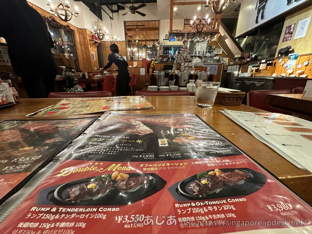 テーブル席から見た店内の様子。手前には大きく広げられたメニュー表があり、奥には赤いソファ席やセルフエリアが見える。