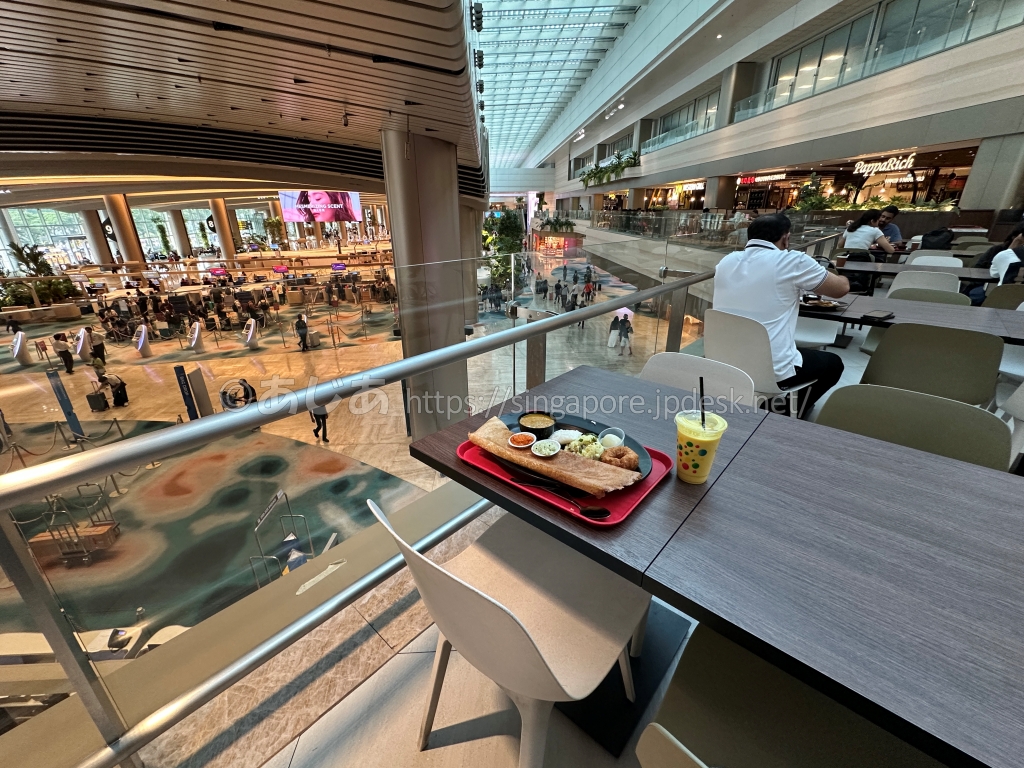 空港ロビーを見渡せるカウンター席と料理のトレー
