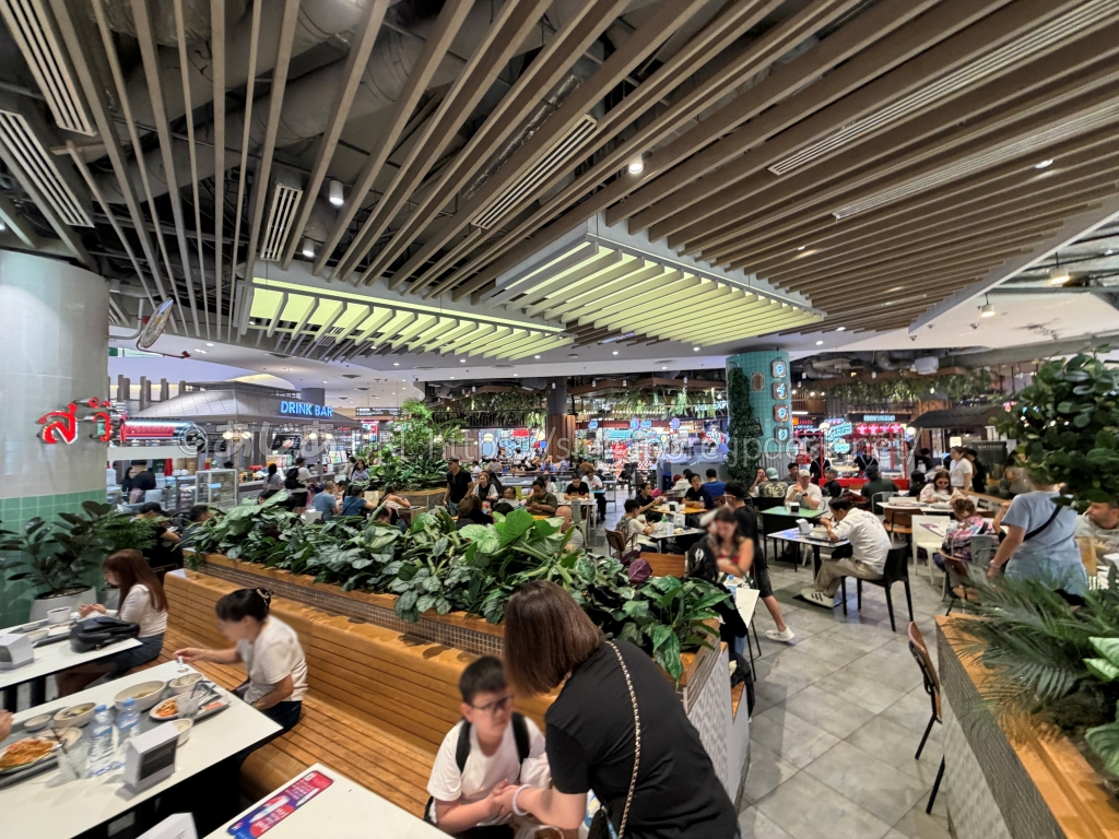 緑の植栽と多数のテーブルが並ぶGOURMET EATSのフードコート