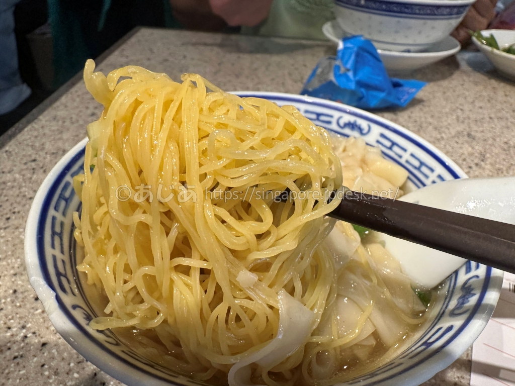 箸で持ち上げた沾仔記の黄色い極細卵麺