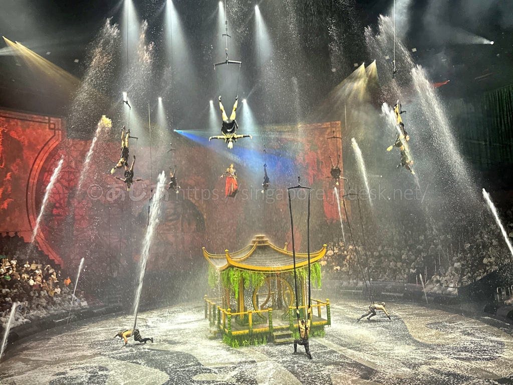 豪雨のような水の中で空中演技を行う出演者