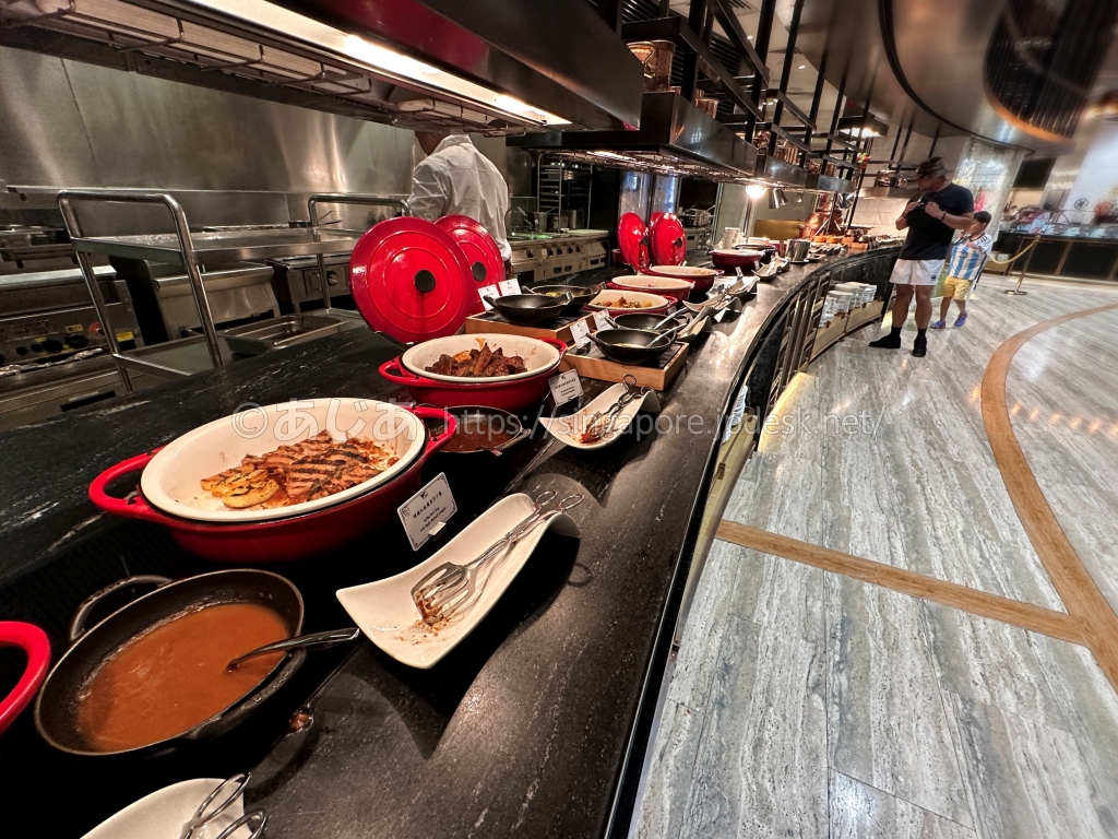 スポットライトの赤い鍋に入った洋食の温菜とソース