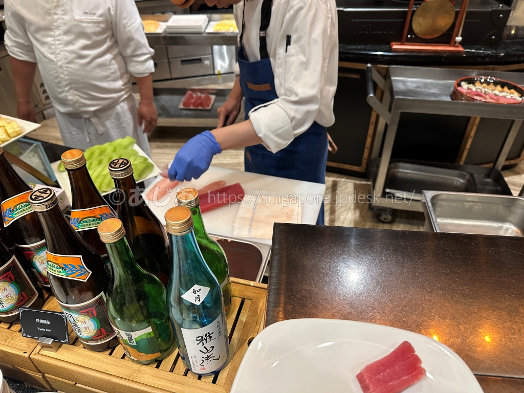スポットライトのライブカウンターでマグロを切り分けるスタッフ