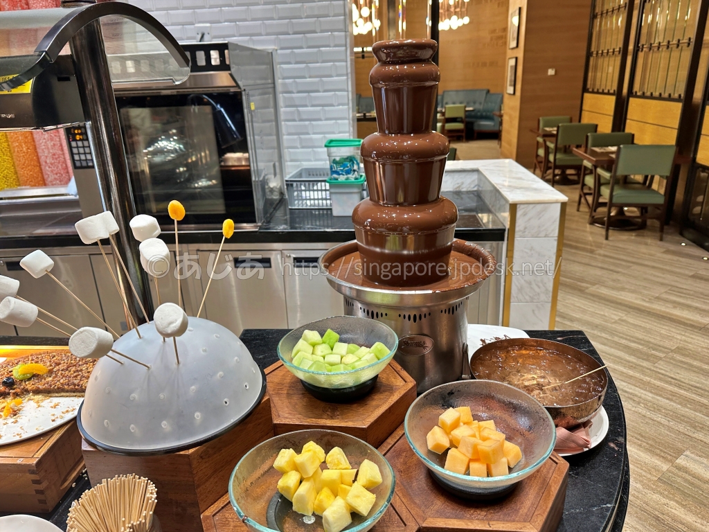 スポットライトのチョコレートファウンテンとマシュマロ、フルーツ