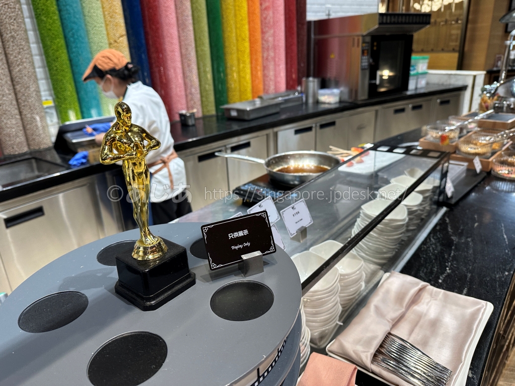スポットライトのライブキッチンに飾られた映画賞風の金色のトロフィー