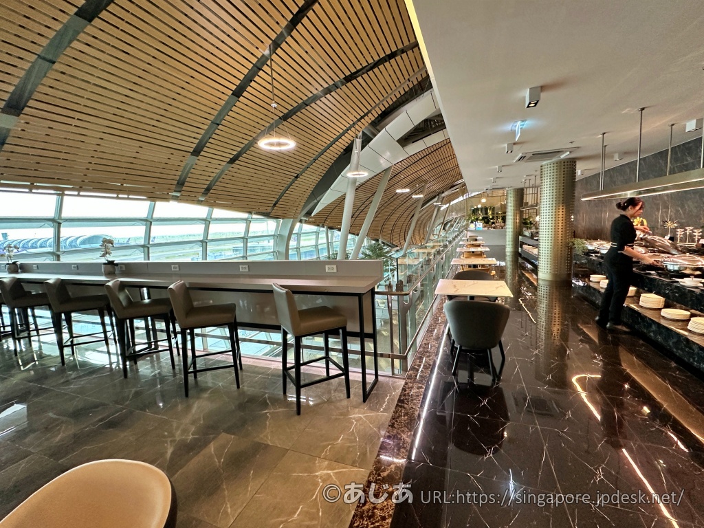 スワンナプーム空港サテライトのMiracle First Class Loungeの窓側席とフードエリア