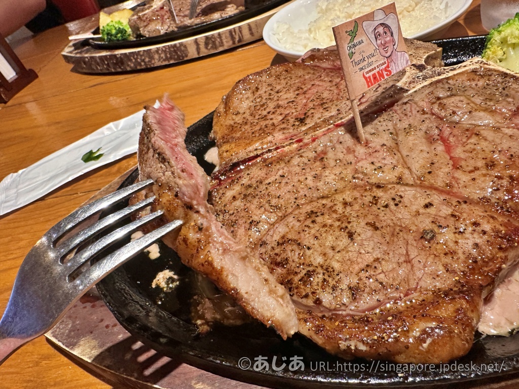 フォークで持ち上げたTボーンステーキの断面。中はピンク色で、表面は香ばしく焼き上がっている。